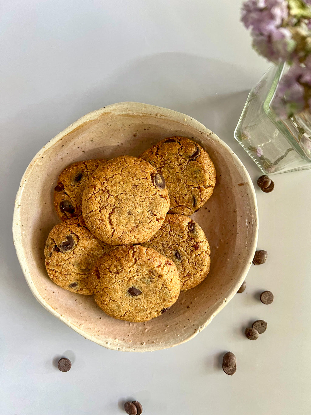 Bowl of Almond & Peanut Butter Cookie with chocolate chips on a light surface