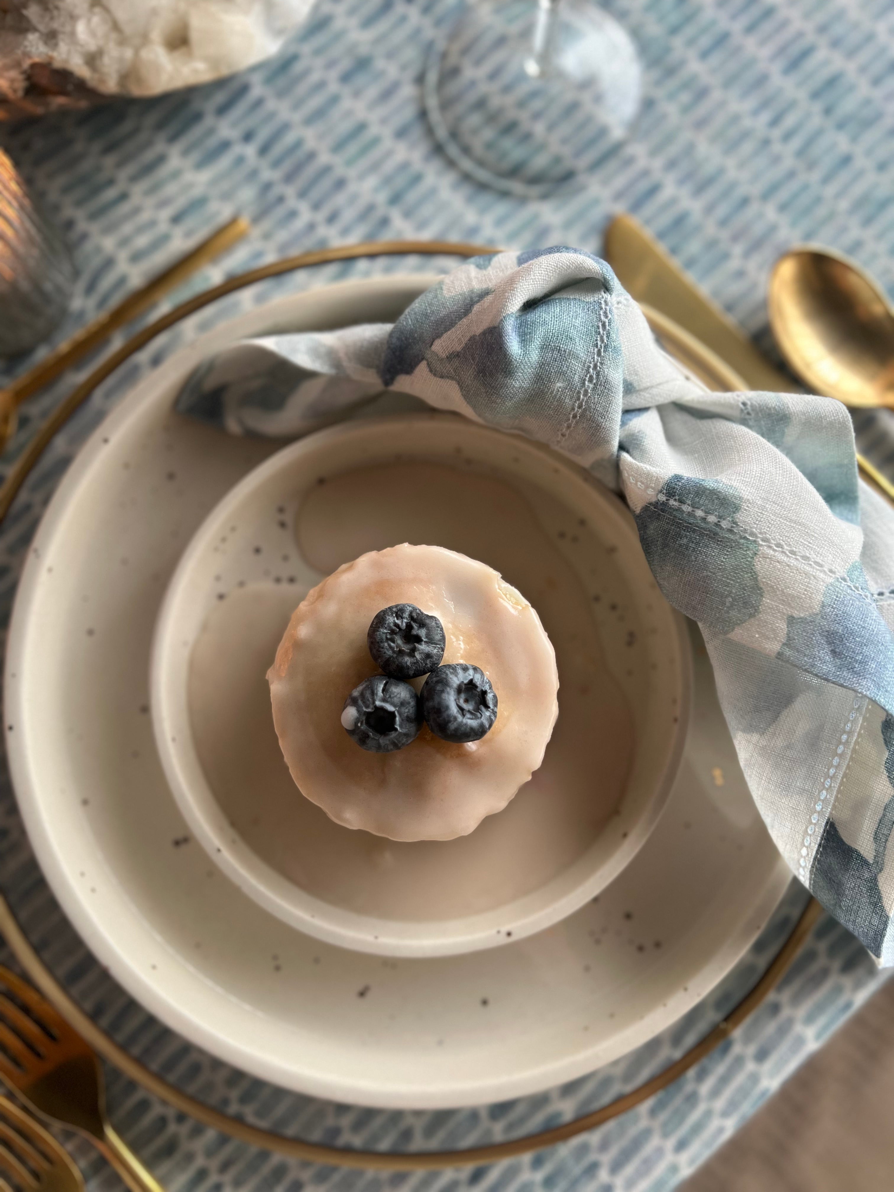 Small dessert with blueberries on a ceramic plate, placed on a patterned tablecloth.