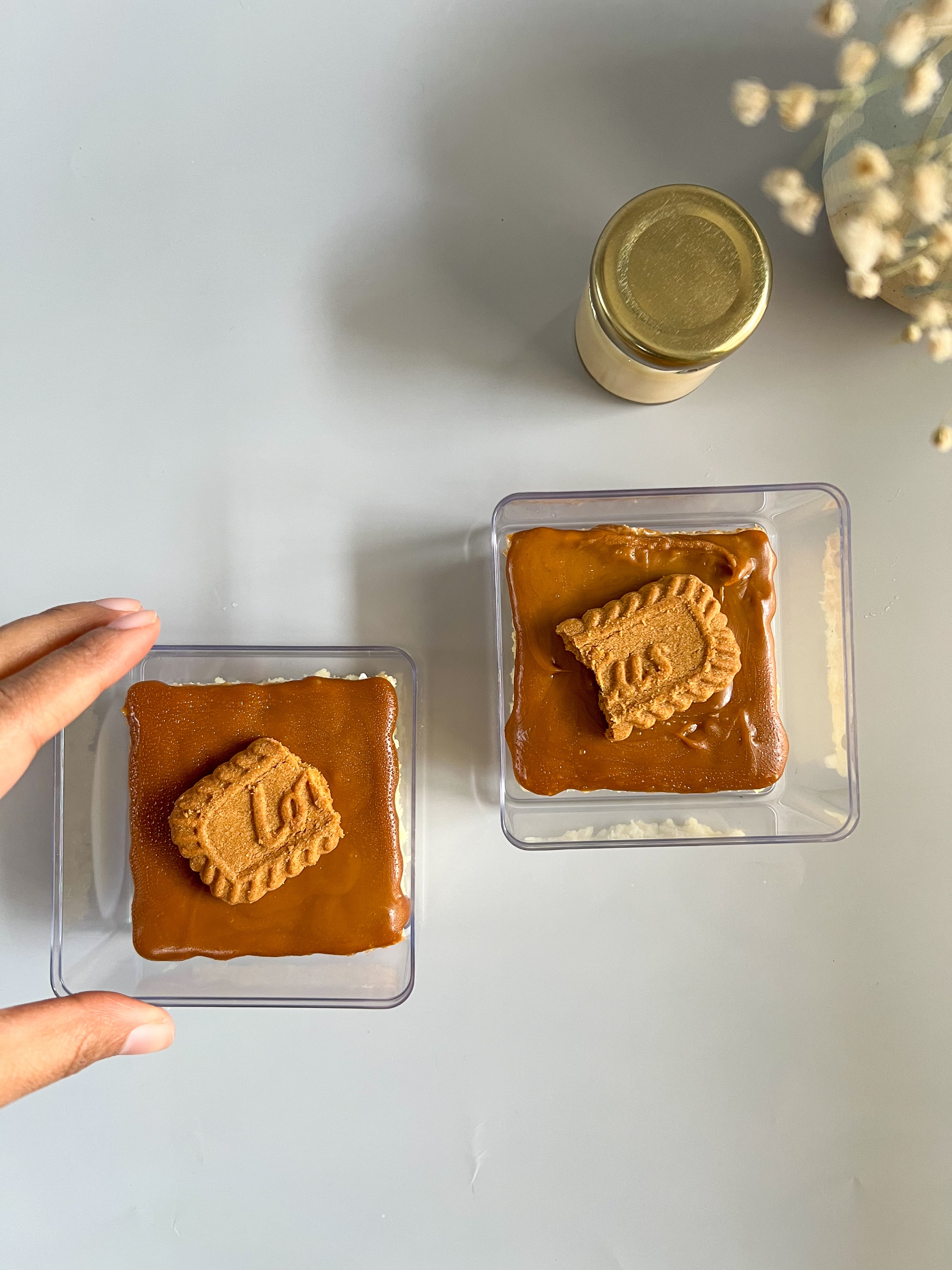 Two square containers with lotus biscoff on a light gray background.